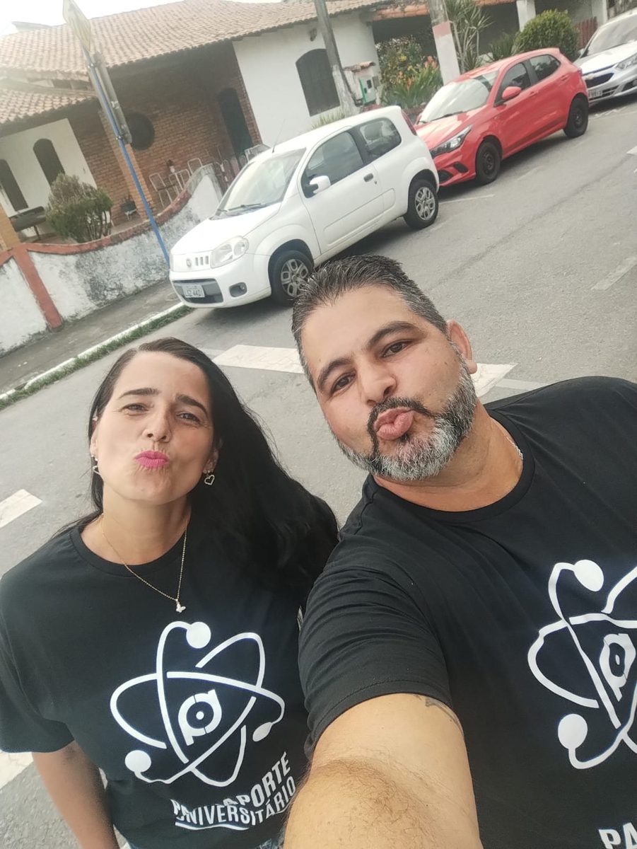 Maurício e Mariana de camiseta preta igual, fazendo biquinho para a selfie na rua.