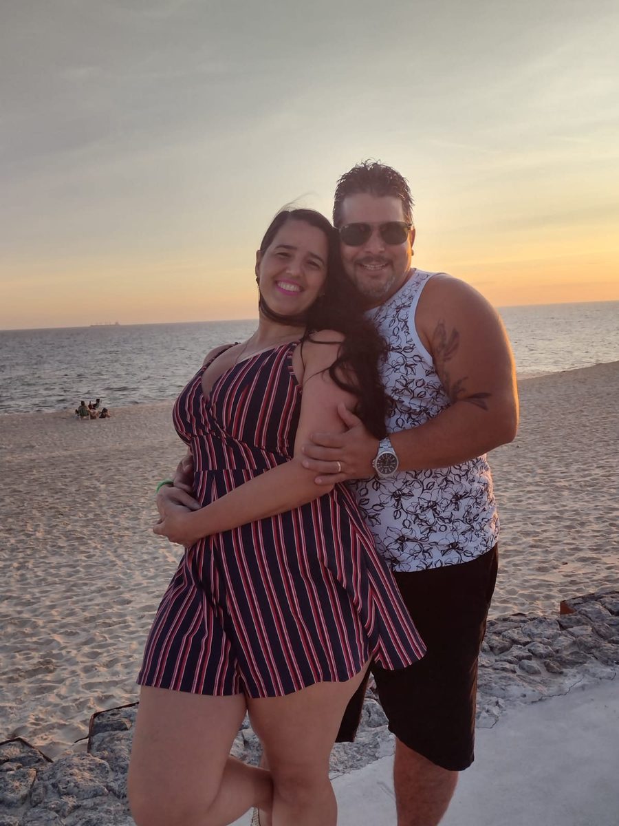 Maurício e Mariana abraçados na praia no fim da tarde.