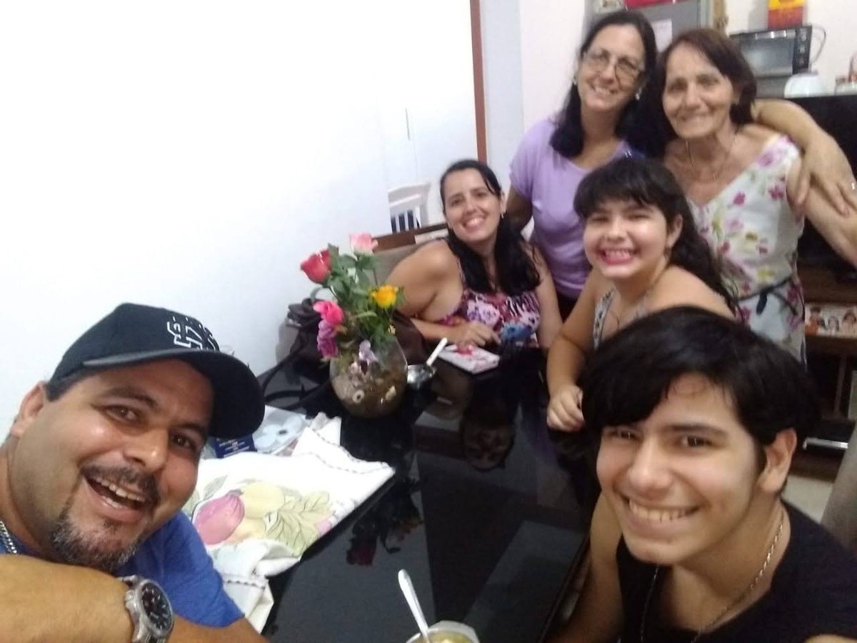 Maurício em selfie com Daniel, Débora, Mariana e as duas avós reunidos na sala.