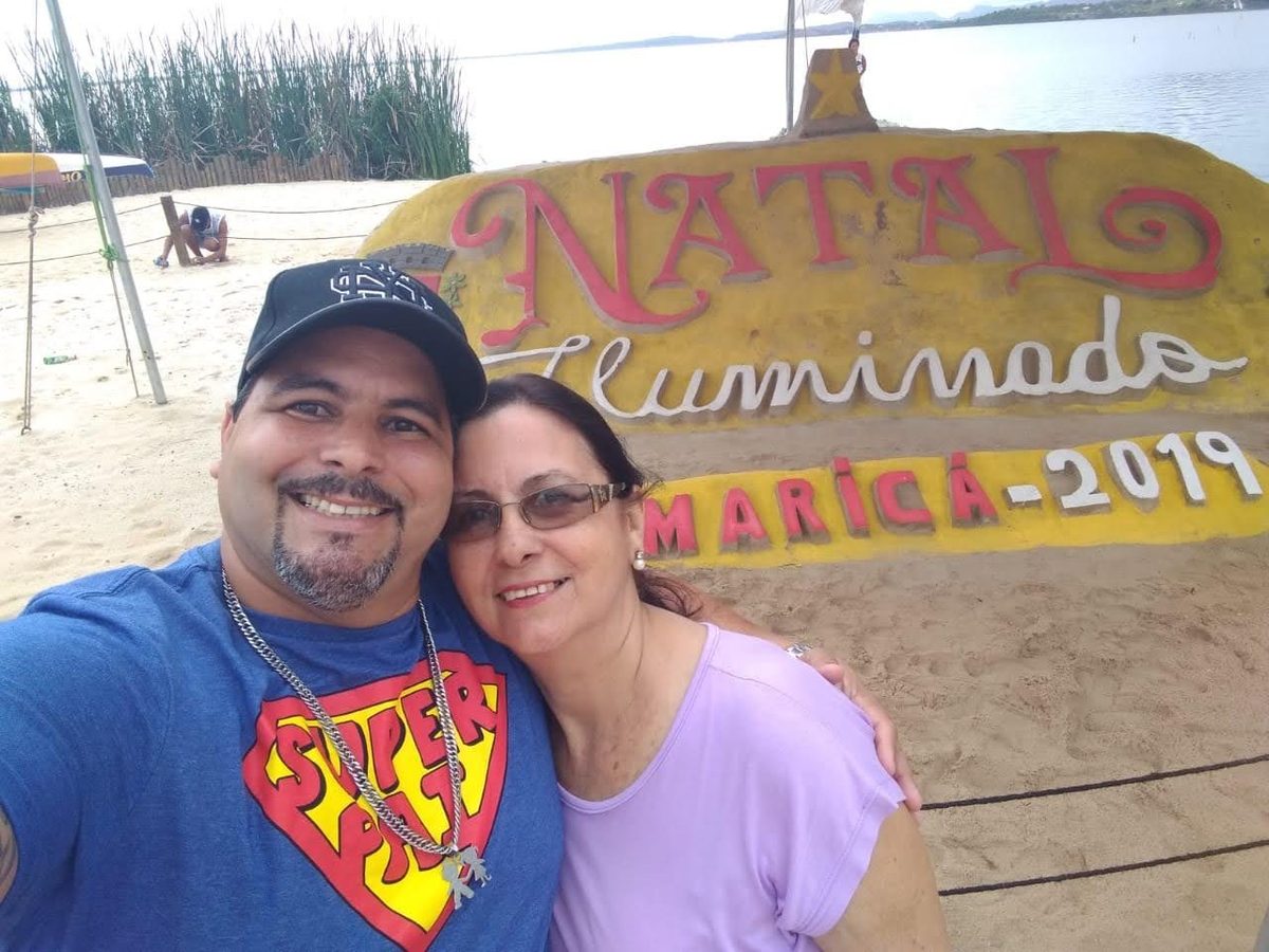 Maurício abraçado com a mãe, dona Linete, na frente do letreiro do Natal Iluminado de Maricá 2019.
